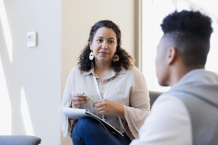 The counselor listens to the young adult and takes notes for their next meeting.